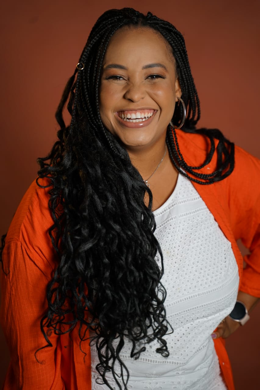 Retrato de Fernanda Silva sorrindo com camisa laranja